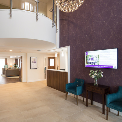Reception desk, Purple wallpaper, mooi lighting, teal chairs and cream tiled floor