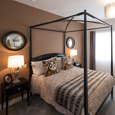Dramatic bedroom, with dark furniture, a four-poster bed and amber accessories 