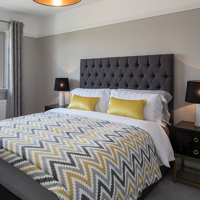 lux bedroom, with charcoal grey and gold cushions and throw