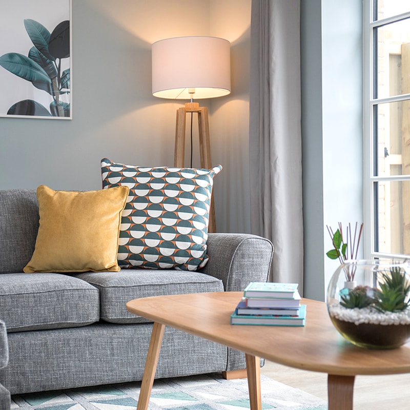 Scandi-style lounge, with grey sofa and palm prints