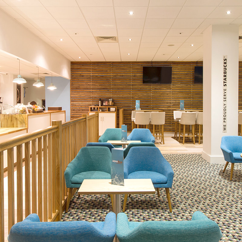 Aqua Lounge Café, with Starbucks coffee bar. Teal and Blue seating, patterned carpet and timber feature walls.